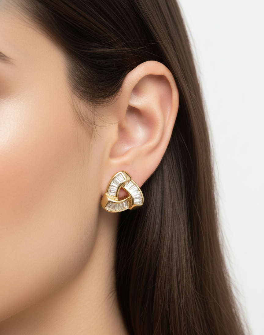 Close-up of woman's ear wearing gold geometric earrings with embedded baguette-cut diamonds