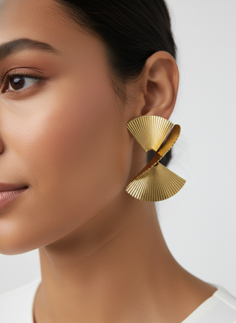 Close-up of woman wearing unique gold geometric fan-shaped earrings on white background